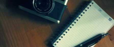 Camera, notebook, and pen on a table