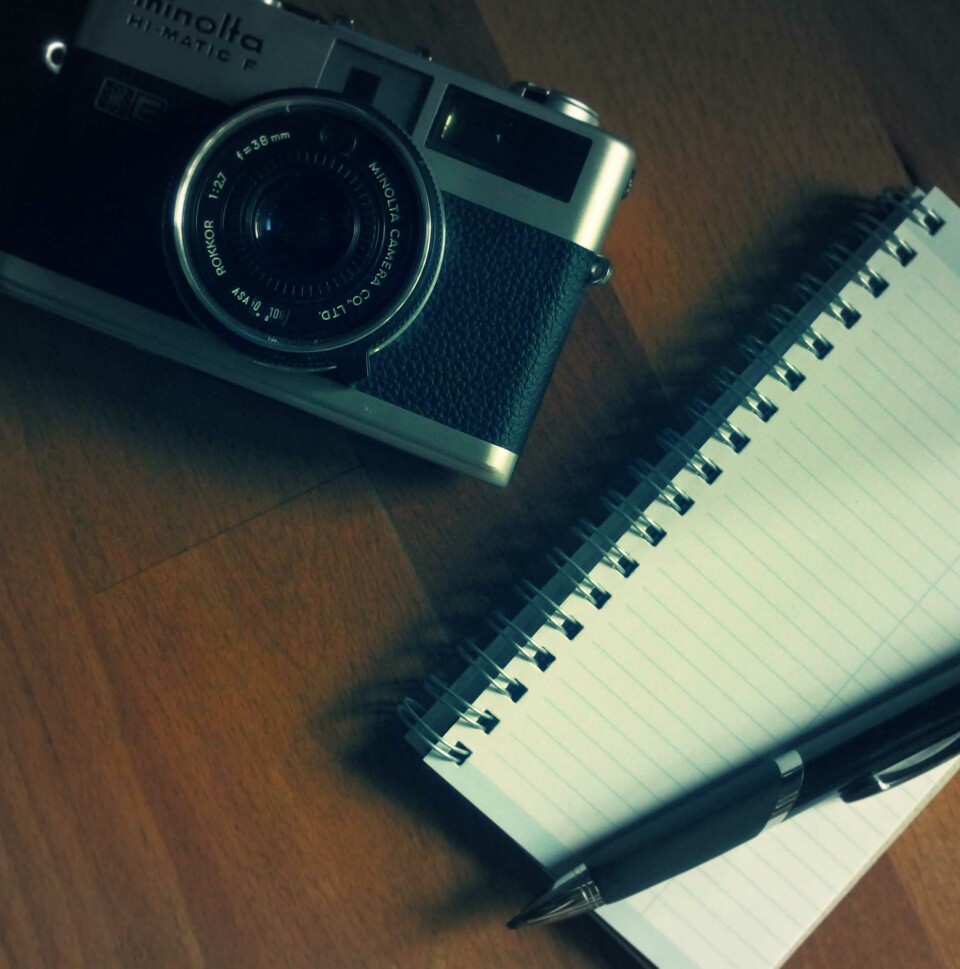 Camera, notebook, and pen on a table